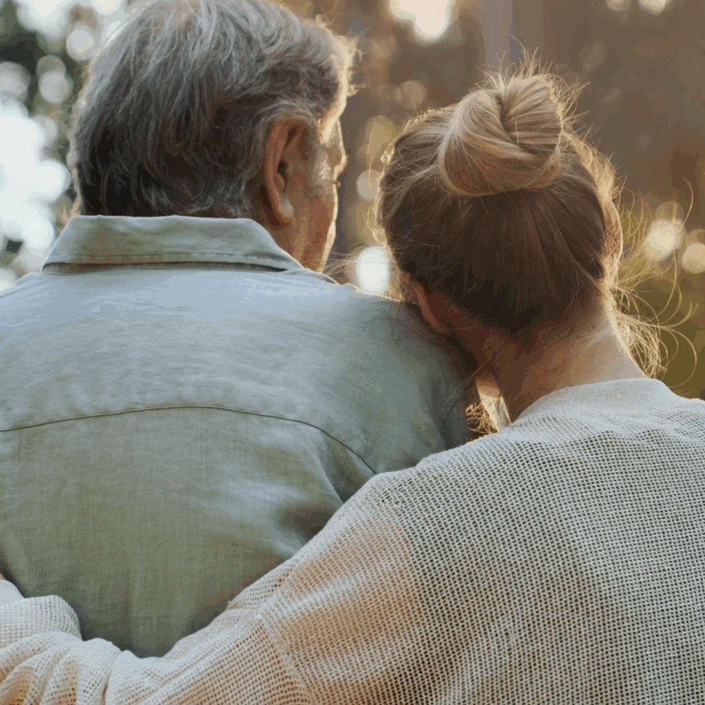 Elderly person and woman embracing outdoors.